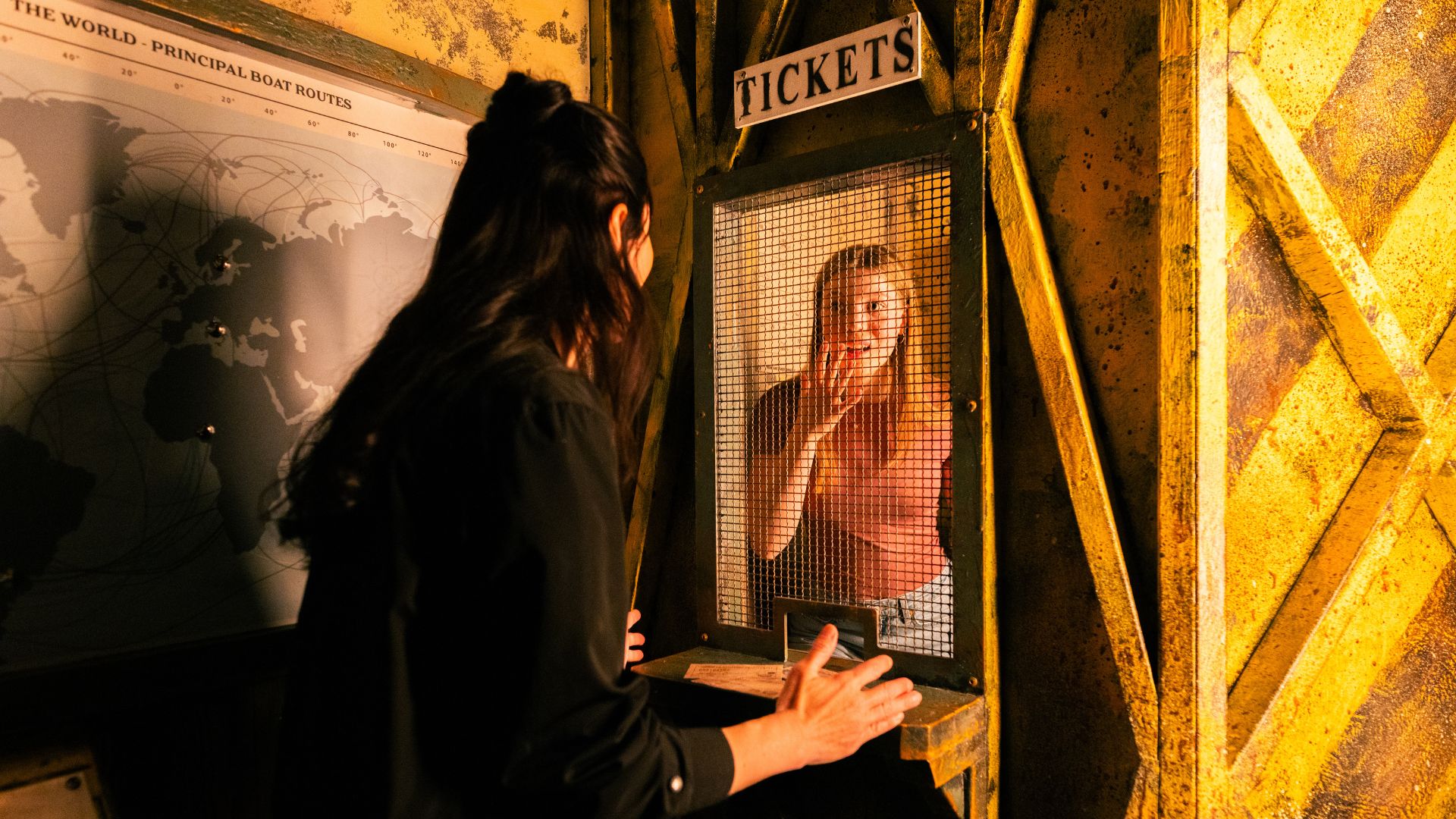 Two young women in a prison cell-style ticket booth
