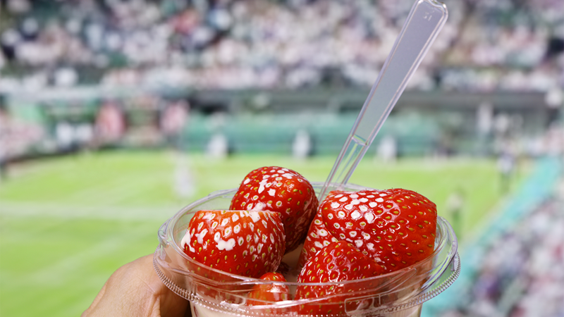 Enjoy a quintessential strawberries and cream at Wimbledon. Credit: Shutterstock. Image courtesy of Shutterstock. A cup of strawberries and cream against a backdrop of a Wimbledon court