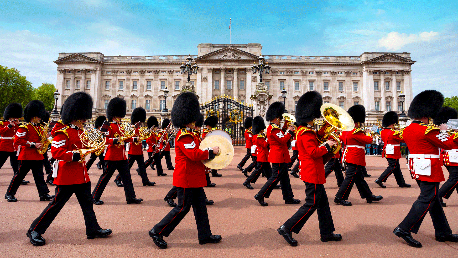 Changing the Guard ceremony outside Buckingham Palace. Image courtesy of Shutterstock. Band marches in front of Buckingham Palace during Changing the Guard