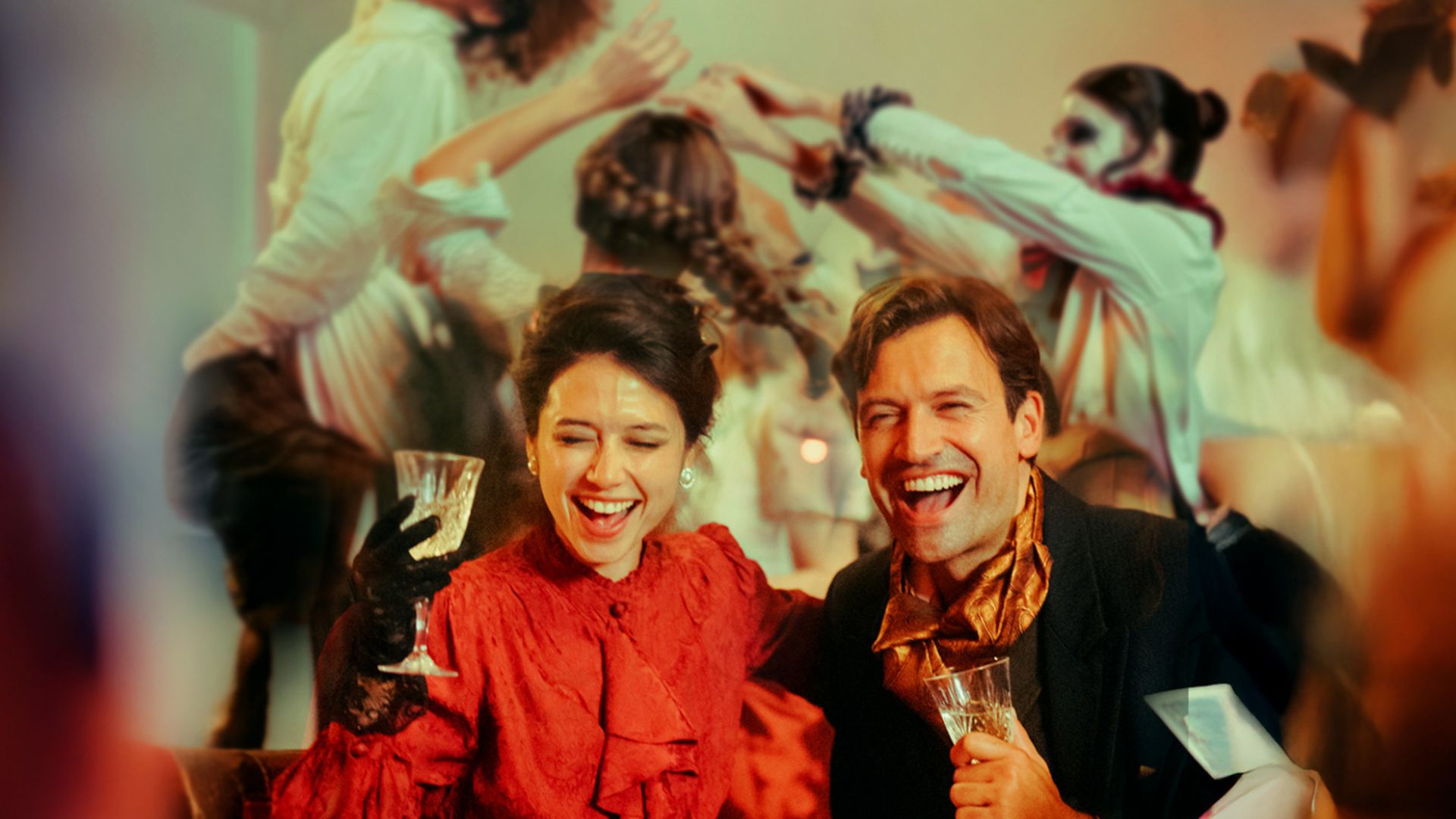 Step into a world of elegance and intrigue at CHAT NOIR – where every toast feels like a scene from a bygone era. Image courtesy of The Lost Estate. Two guests dressed in vintage-inspired attire enjoying cocktails, with lively dancers performing in the background at CHAT NOIR.
