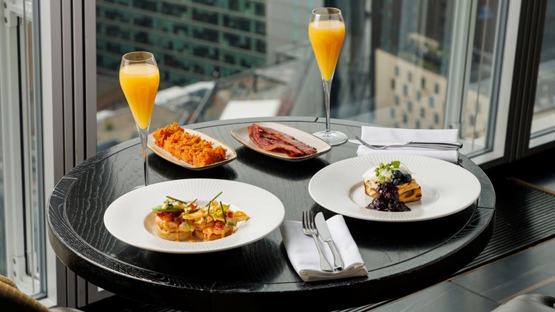 Experience a fine dining brunch in one of London's most famous buildings at Aqua Shard. Credit: Aqua Shard. Image courtesy of Aqua Shard. A photo of a table at Aqua Shard filled with brunch dishes and two flutes with mimosas with a background of a view over London through floor-to-ceiling windows