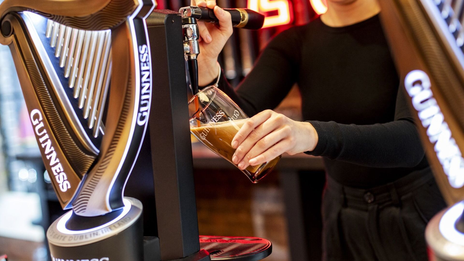 Visitors can learn how to pour the perfect pint during the Guinness Open Gate Brewery experience. Image courtesy of Golden Tours. Person pouring a Guinness from a branded tap during the Guinness brewery tour in London.