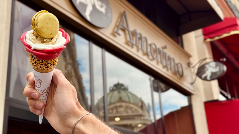Delight in an iconic Amorino rose-shaped ice cream. Credit: Amorino. Image courtesy of Amorino. A person holding a rose-shaped ice cream against the Amorino shop front
