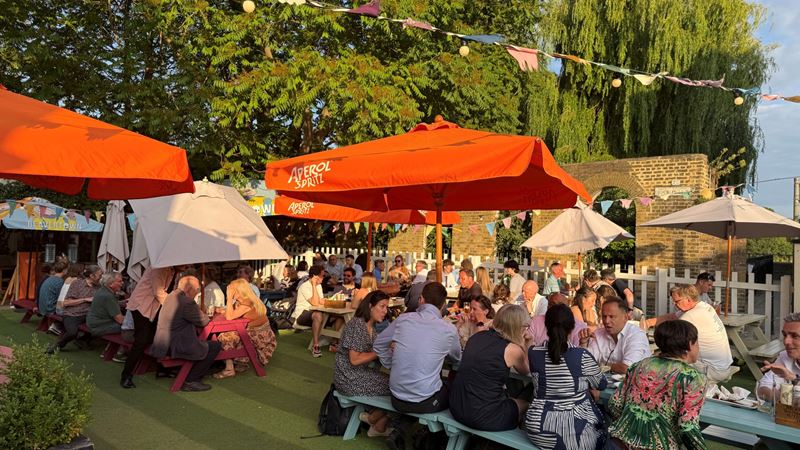 Take a seat in The Black Lion's outdoor garden, situated next to the river Thames. Credit: The Black Lion. Image courtesy of The Black Lion. Benches full of people enjoying drinks on a sunny afternoon with bunting and parasols overhead and trees in the distance