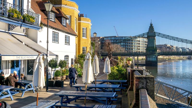 Sip on pints in the sunshine from the benches in front of The Blue Anchor in Hammersmith. Credit: Shutterstock. Image courtesy of Shutterstock. A photo of the exterior of The Blue Anchor on the river Thames on a bright sunny day with blue picnic benches outside the front