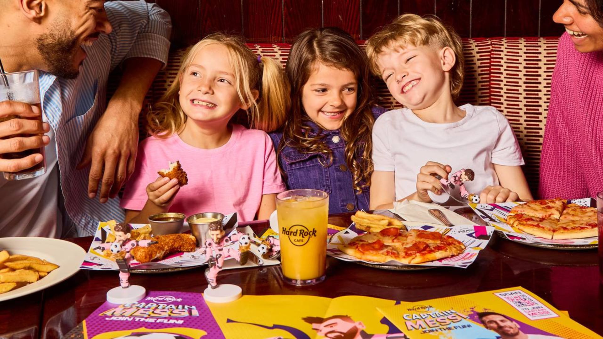 Smiles, sharing plates and a little rock ’n’ roll - family dining at Hard Rock Cafe. Image courtesy of Hard Rock Cafe. Family enjoying pizza, chicken and drinks together in a lively Hard Rock Cafe restaurant.
