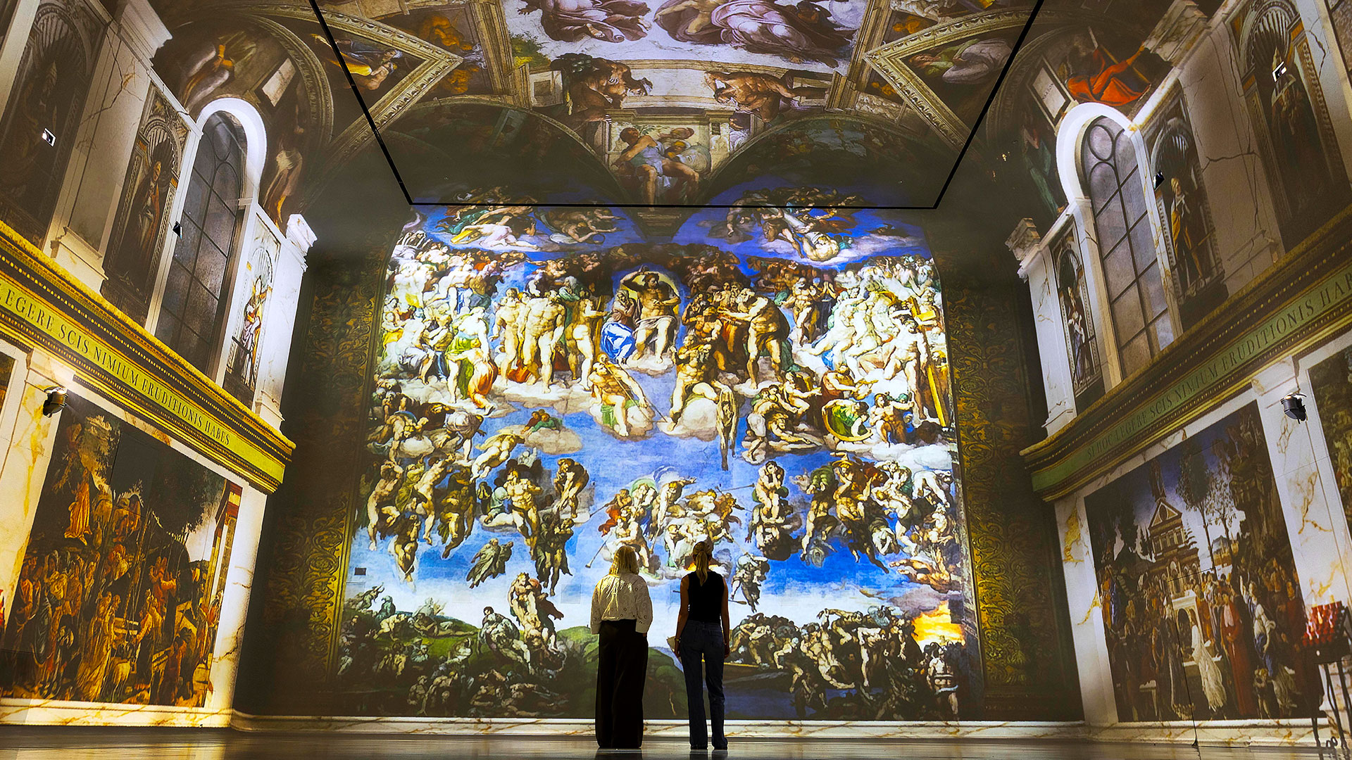 This summer, see FRAMELESS's immersive art gallery transform into the Sistine Chapel, bringing Michelangelo's masterpiece to life. Image courtesy of Mance Communications. Two people are admiring one of FRAMELESS's galleries, which has been transformed into the Sistine Chapel with projections of Michelangelo's famous frescoes.