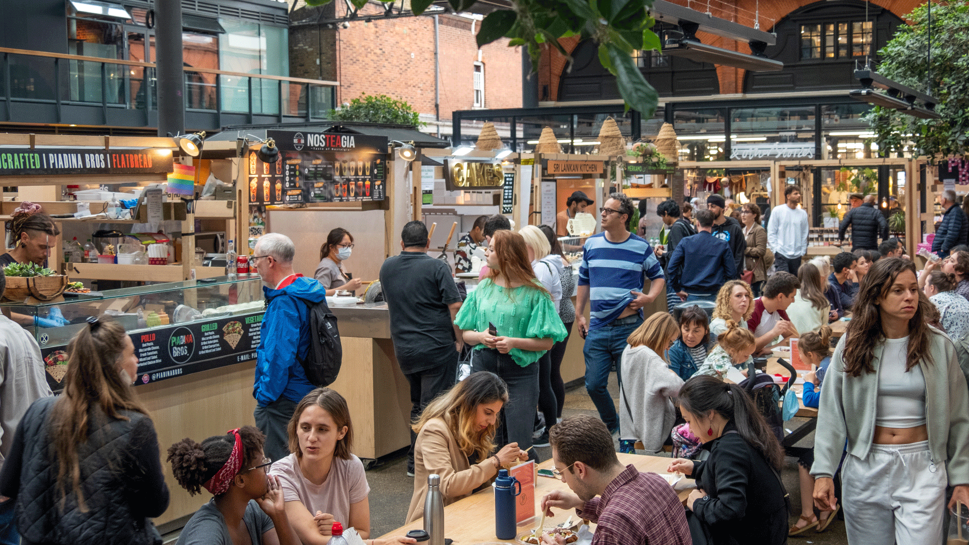 Find mouthwatering food from around the world at Old Spitalfields Market. Credit: Shutterstock. Image courtesy of Shutterstock. People gathered in Old Spitalfields Market buying food from stalls and eating it on nearby tables