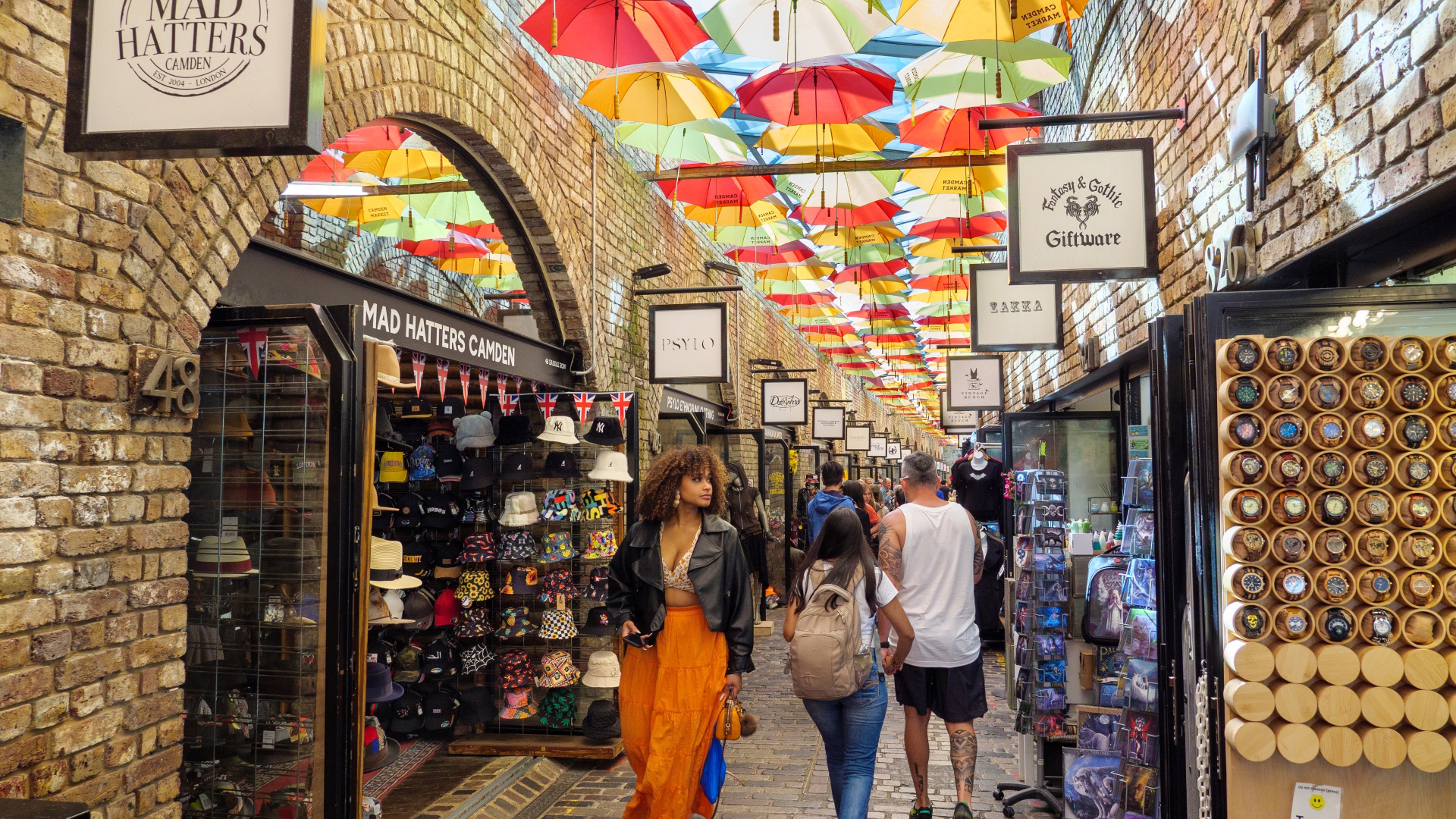 Make your way around Camden's artisan shops selling locally sourced and handmade goods. Credit: Shutterstock. Image courtesy of Shutterstock. A photo inside Camden Market with people walking past shops selling different products and multicoloured umbrellas forming a roof above
