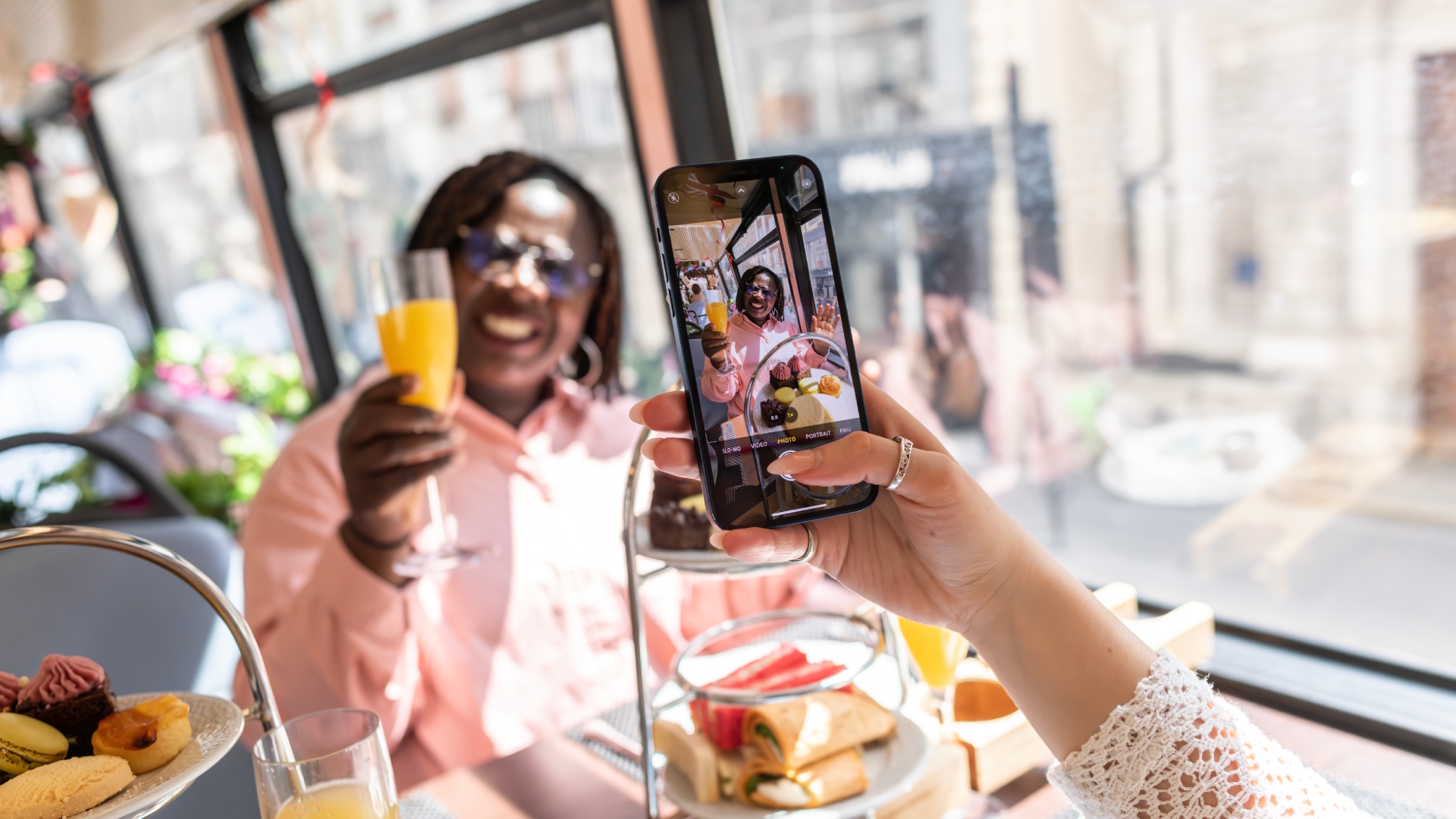 See London's top sights on an afternoon tea bus tour. Image courtesy of London & Partners/Michael Barrow. A woman poses with a glass of orange juice on an afternoon tea bus tour
