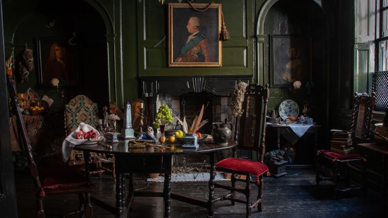 Glimpse at artist Dennis Severs' former home on a tour of his house in London. Credit: Lucinda Douglas Menzies. Image courtesy of Dennis Severs' House. A dark wooden table laid with fruits, candles and feathers inside Dennis Severs' House in London, with paintings on the walls and dark wood floorings.