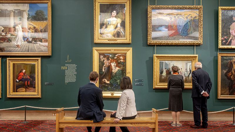 Discover paintings from 1670 to the 21st century at Guildhall Art Gallery. Image courtesy of Guildhall Art Gallery. Two people sitting and two other people standing in front of paintings at Guildhall Art Gallery.