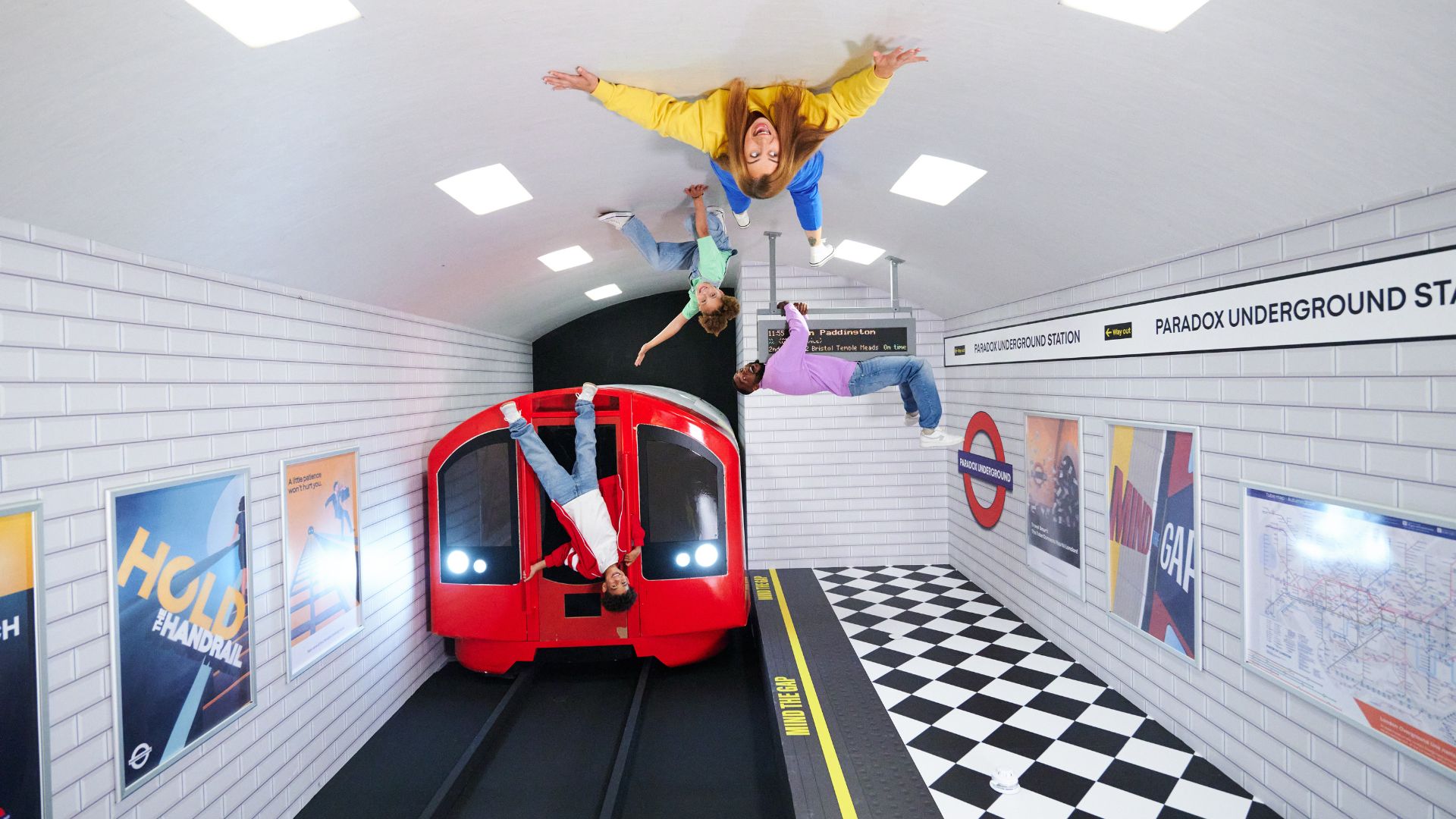 Strike a pose in the Reversed Room at Paradox Museum. Image courtesy of Golden Tours. Group of people posing within an illusion that looks like they're hanging upside down in a London tube station.