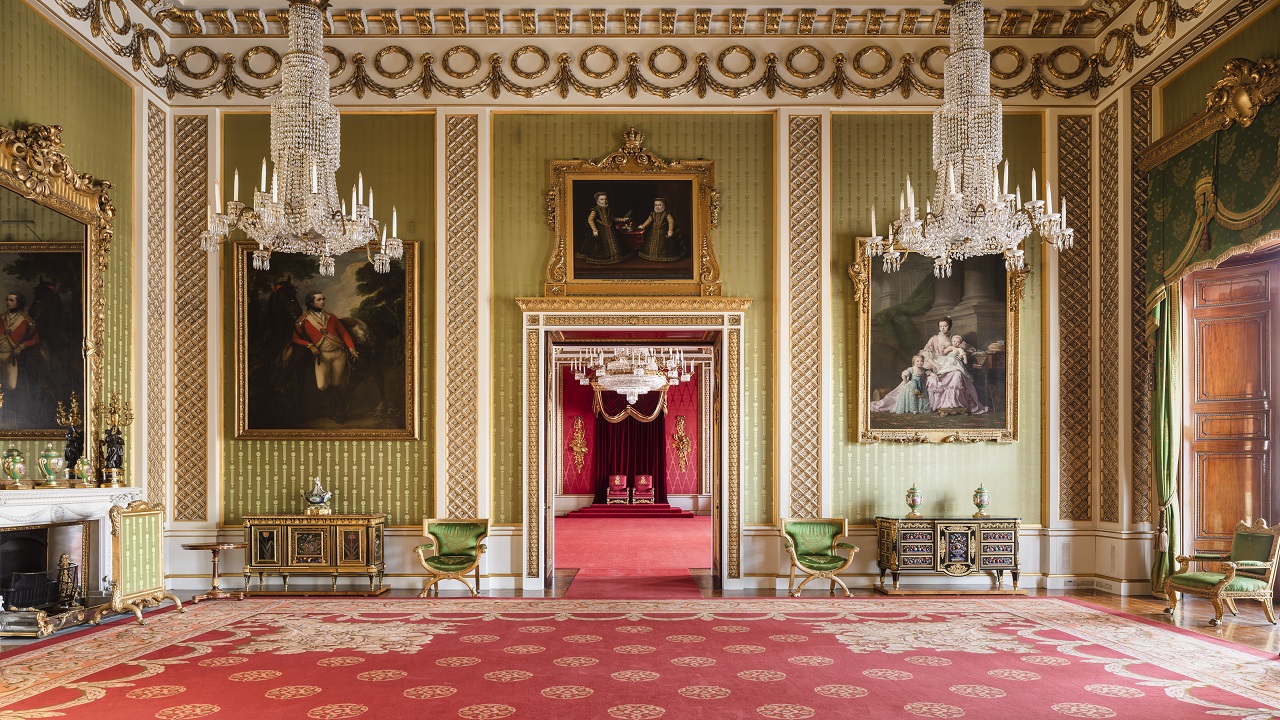 Green Drawing Room at Buckingham Palace. Image courtesy of Royal Collection Trust / © His Majesty King Charles III 2023. Landscape photo of the Green Drawing Room in Buckingham Palace; royal gold and red carpet, green panelled walls with large portraits hanging, high ceilings decorated in gold, green and gold furniture in the room