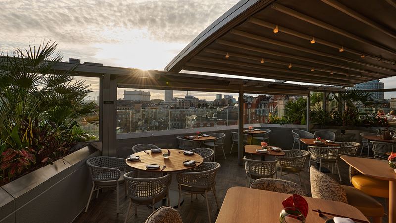 The terrace at Radio Rooftop. Image courtesy of Upmarket Hotels & Leisure Ltd. Tables and chairs on the terrace with a partially open roof above.