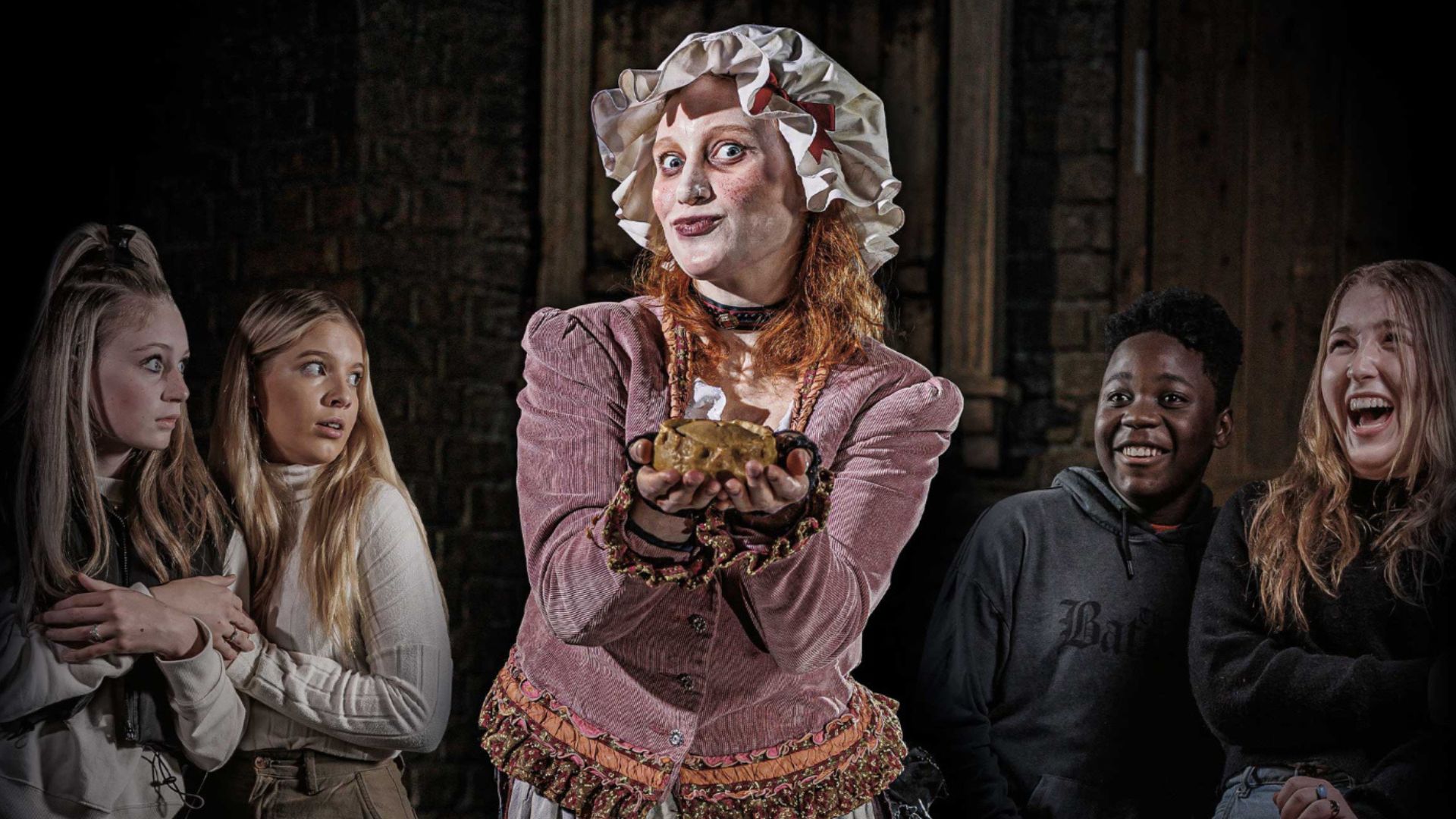 Step into Mrs Lovett's famous pie shop in Fleet Street – she might even make YOU a pie! Image courtesy of The London Dungeon. female actor stood in the middle, dressed in Victorian clothes holding a pie, with four people stood around her smiling and in shock