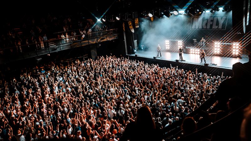 See world famous acts at the 3,800 capacity British Airways ARC. Credit: Olympia. Image courtesy of Olympia. A photo of the crowd at Blues Kitchen in Camden. Everyone is smiling with their hands in the air facing the stage as confetti falls from above