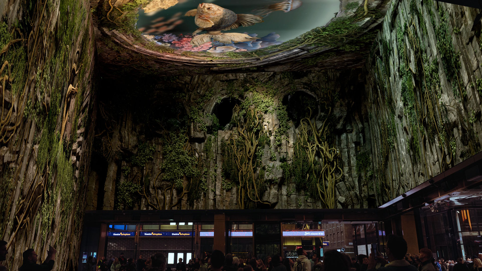 Outernet's Intelligence Garden immersive show shown on its large-scale LED screens. Image courtesy of Outernet. A display on Outernet's large wrap-around LED screens, showing green plants and vines tumbling down from the ceiling, where there's an image of a large fish.