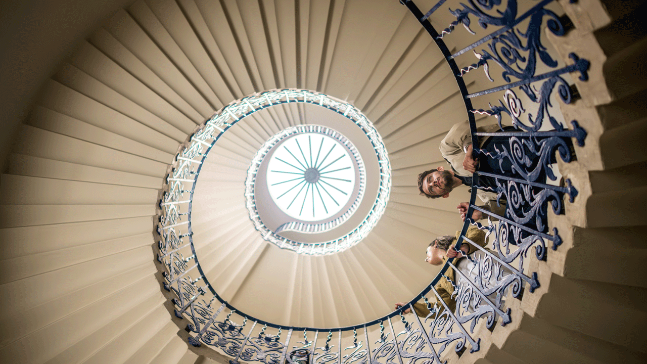 Admire the Tulip staircase at the Queen's House, an historic sight in Greenwich. Credit: Michael Barrow. Image courtesy of visitlondon.com. A man and a woman are looking down from the top of a spiralled staircase at the Queen's House in Greenwich.