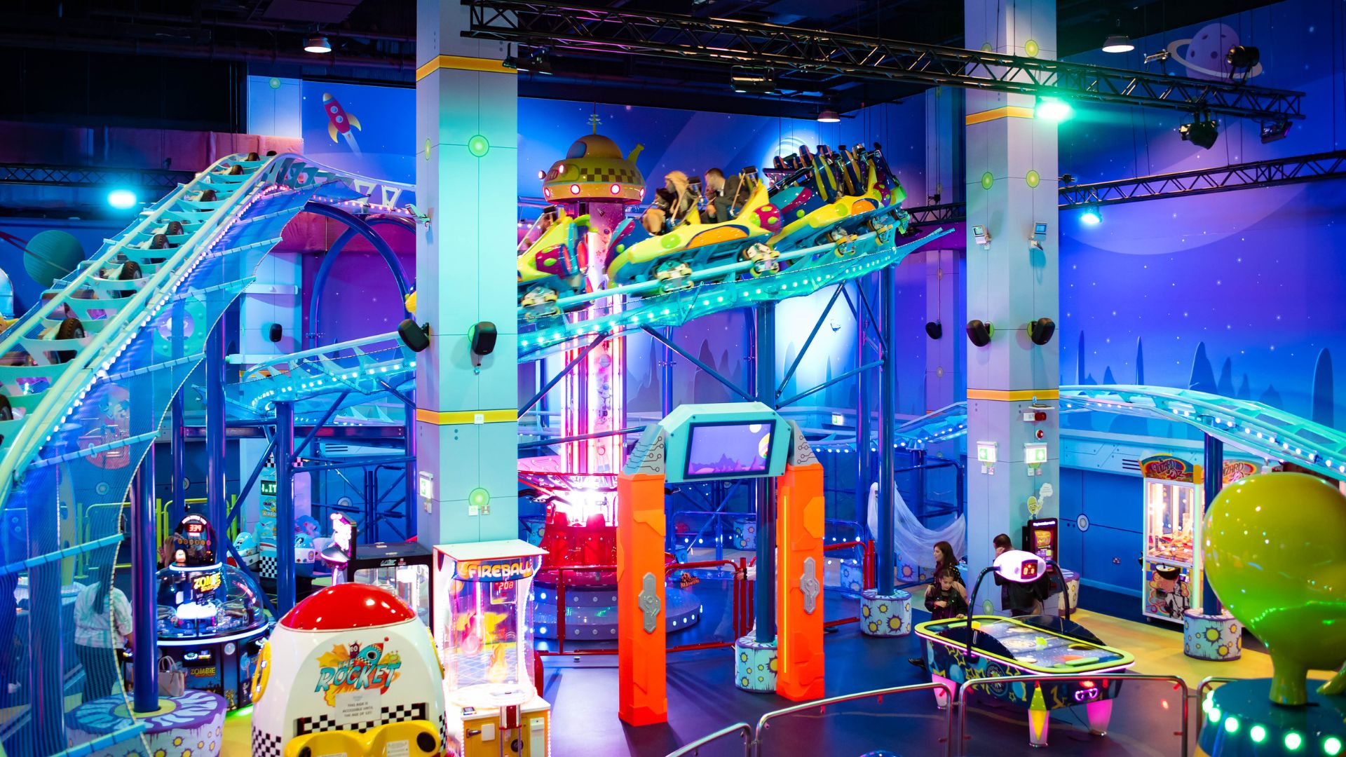 Experience indoor rides, games and family fun at Babylon Park, London's only indoor amusement park. © Devon Shoob/Babylon Park Brightly lit indoor amusement park with roller coaster rides, arcade games, and space‑themed décor.