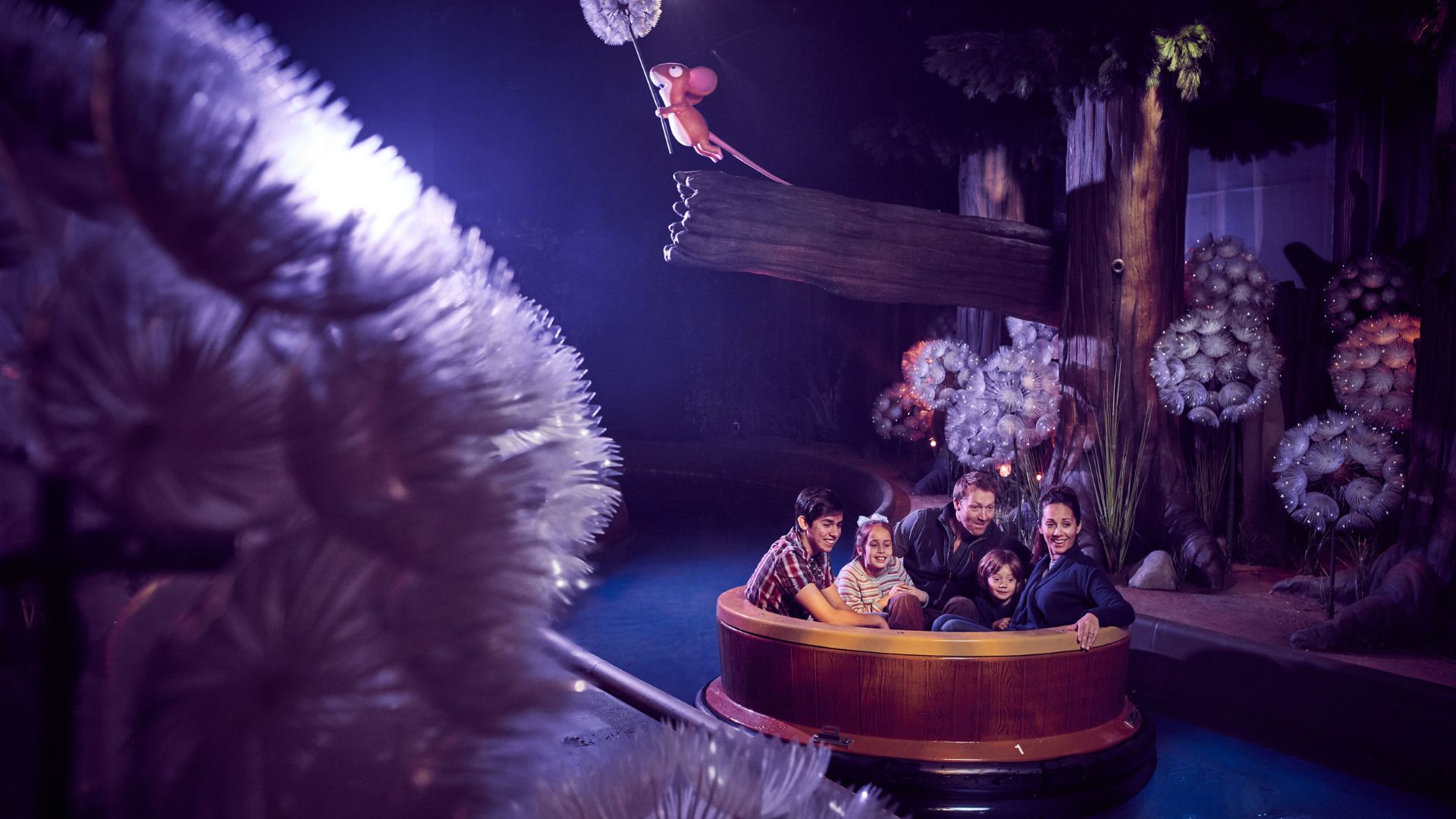 Journey along the lazy river on the Gruffalo River Ride Adventure at Chessington World of Adventures Resort. Image courtesy of Merlin. A family-friendly slow river ride adventure, with two adults and three children smiling and looking at The Gruffalo themed attraction.