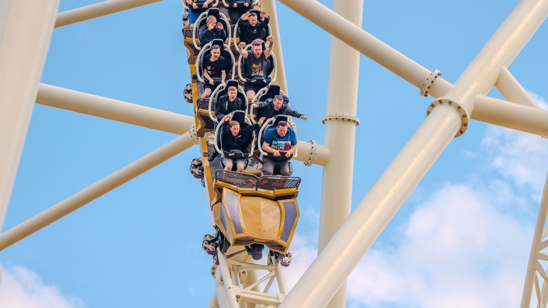 Experience the thrill of Hyperia, the UK's tallest, fastest and most weightless rollercoaster, at Thorpe Park Resort. Image courtesy of Merlin. Riders seated on the Hyperia roller coaster at Thorpe Park as the train descends a steep drop against a blue sky.