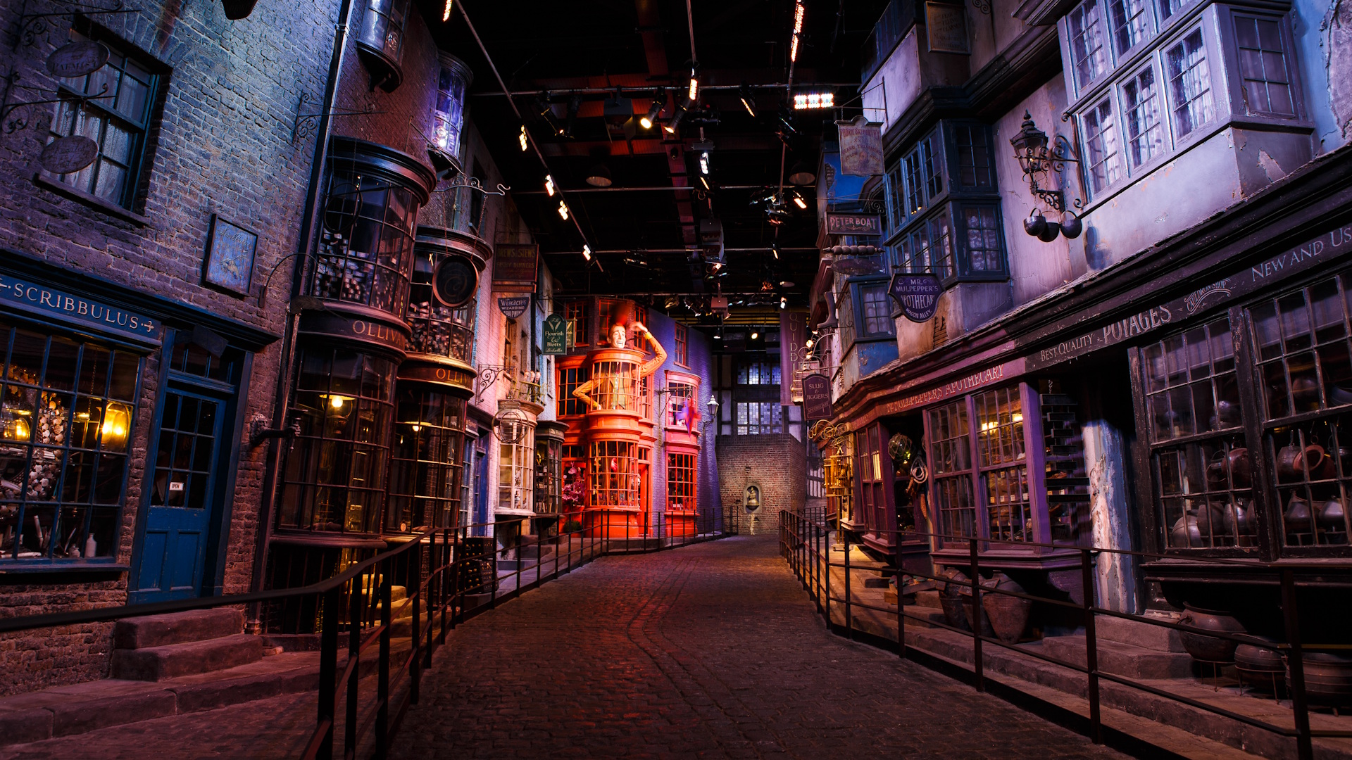 Diagon Alley. Credit: Warner Bros. Studio Tour London – The Making of Harry Potter. Image courtesy of Golden Tours. The set of Diagon Alley at the Warner Bros. Studio Tour in London, featuring empty and darkly lit alleyway with brick buildings and a red facade in the distance.