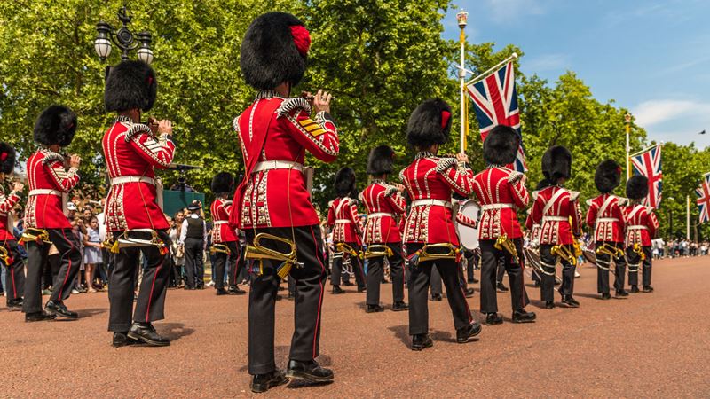 See the guards in iconic red uniforms as they parade during Trooping the Colour. Image courtesy of Shutterstock. Military parade of troops from the Household Division honouring the King's official birthday during Trooping the Colour in London.