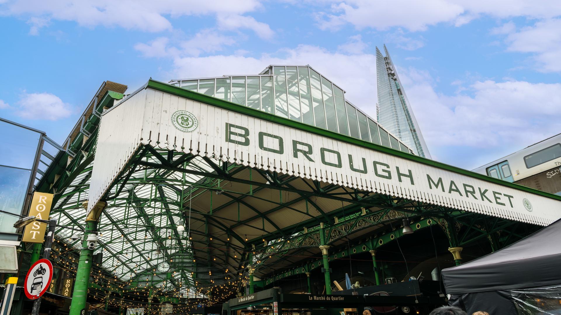 Borough Market, a historical market in Southwark. Image courtesy of London & Partners/Michael Barrow. low angle photo taken of the Borough Market sign, with the tip of the Shard in the background
