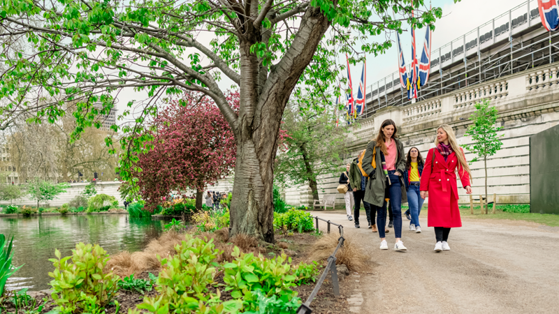 Learn about the history of London on a royal walking tour. Image courtesy of London & Partners/Michael Barrow. A group walking along a river bank on a Royal walking tour