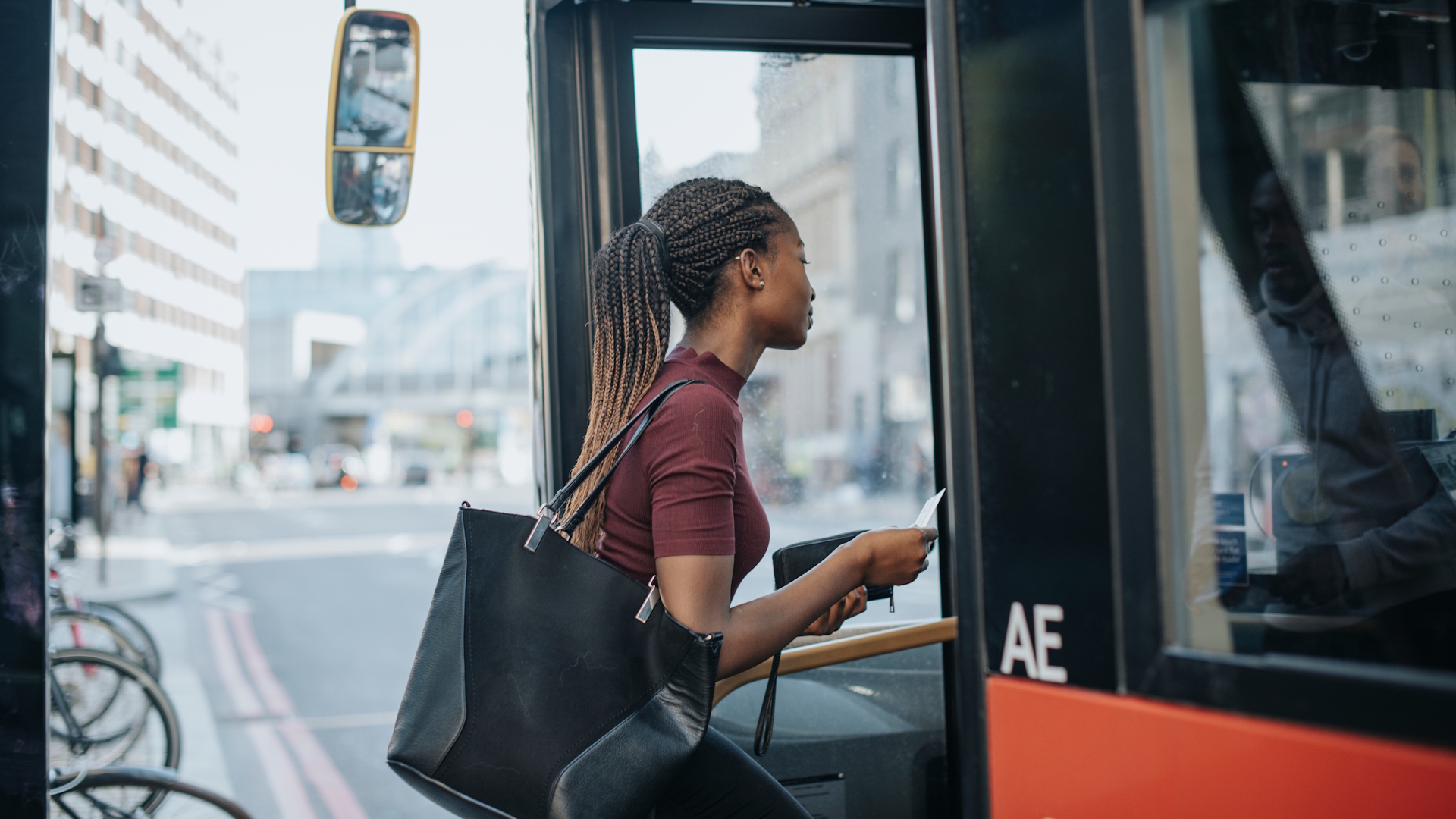 Travelling on the bus in London. Credit: Shutterstock. Image courtesy of Shutterstock. Young black woman boarding a London bus.
