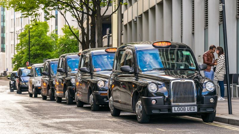 Head to a London taxi cab rank to catch a ride to almost any destination in the city. Credit: Shutterstock. Image courtesy of Shutterstock. A photo of a row of black London taxi cabs lining up at the side of a road waiting for passengers