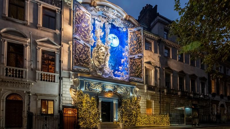 Admire the magical Narnia-inspired display for Christmas this year at Annabel's. Credit: Annabel's. Image courtesy of Annabel's. A close up photo of the Christmas facade on the front of Annabel's members club with wardrobe doors open to reveal a sky at night with the moon above and a giant lion, inspired by Narnia