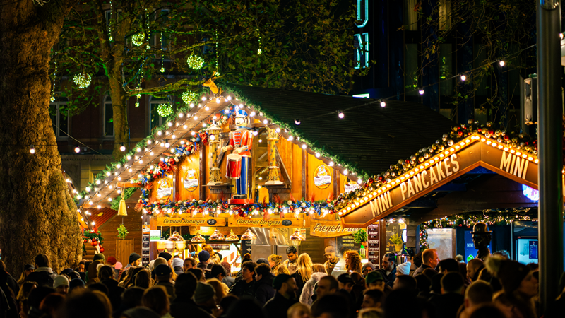 Get in the festive spirit at the Leicester Square Christmas market. Credit: Michael Aiden. Image courtesy of Leicester Square. Warm twinkling lights illuminate a stall at the Leicester Square Christmas market with a toy soldier on the top and crowds of people walking around in front