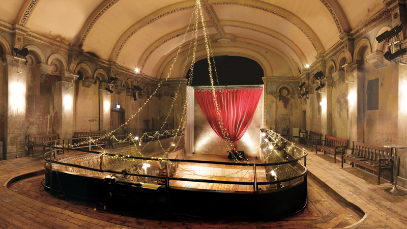 See live events at the grade II-listed Wilton's Auditorium, originally built in 1858. Image courtesy of Wilton's Music Hall. View of Wilton's Auditorium from above with many preserved traditional features including a red curtain on stage