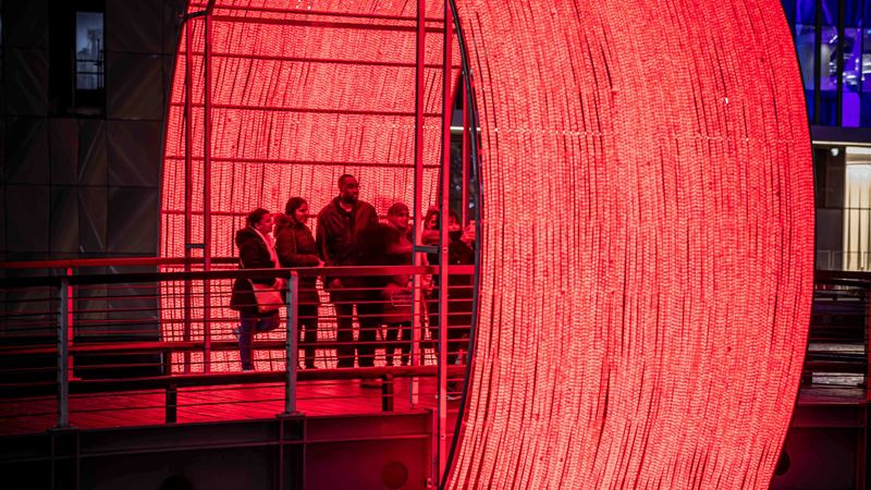 Get immersed in the light art that is scattered around Canary Wharf for its Winter Lights exhibition. Credit: Nunzio Prenna. Image courtesy of Canary Wharf. A group of people stood on a bridge at Canary Wharf with a huge glowing red light installation forming an archway around the bridge