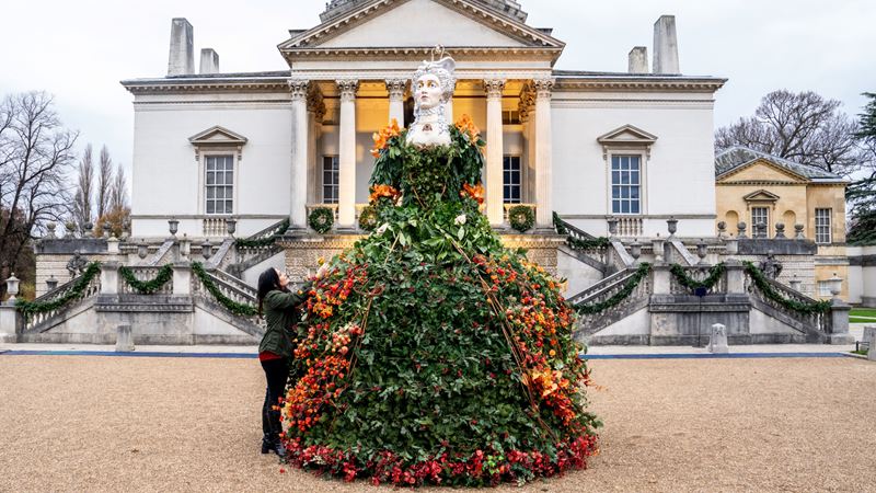 Wander Chiswick House and Gardens as it is dressed up for the festive season in the style of a Georgian Christmas. Credit: Craig Sugden. Image courtesy of Chiswick House. A photo of the statue in front of Chiswick House decorated with colourful plants and flowers in the shape of a giant Georgian dress
