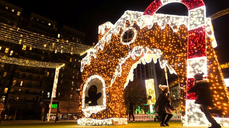 Follow the festive light installations on display around Wembley Park this Christmas. Credit: Amanda Rose. Image courtesy of Wembley Park. A photo of two children running around in front of a giant gingerbread light installation and candy cane at night