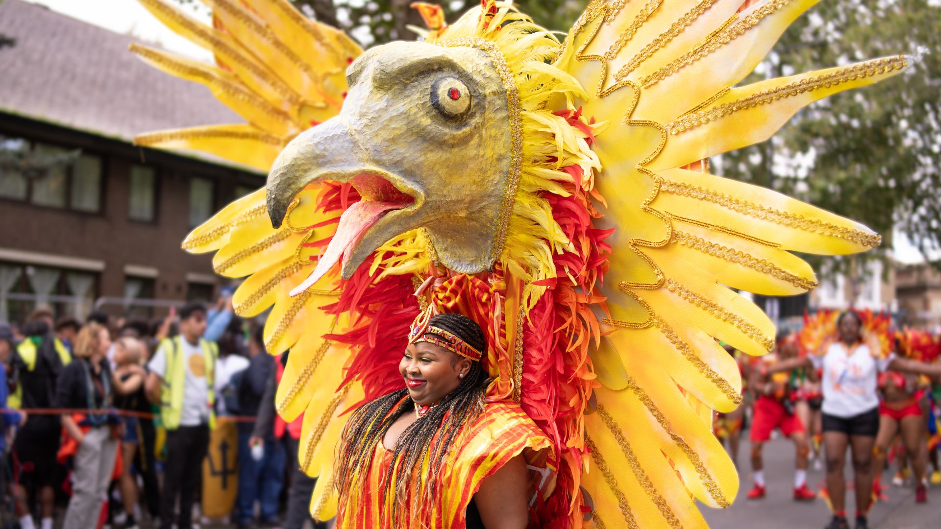 Spot incredible handcrafted costumes inspired by birds, nature and Caribbean traditions at Notting Hill Carnival. Image credit: London & Partners/Peter Cohen. A carnival participant wears an oversized golden bird costume during the Notting Hill Carnival parade.