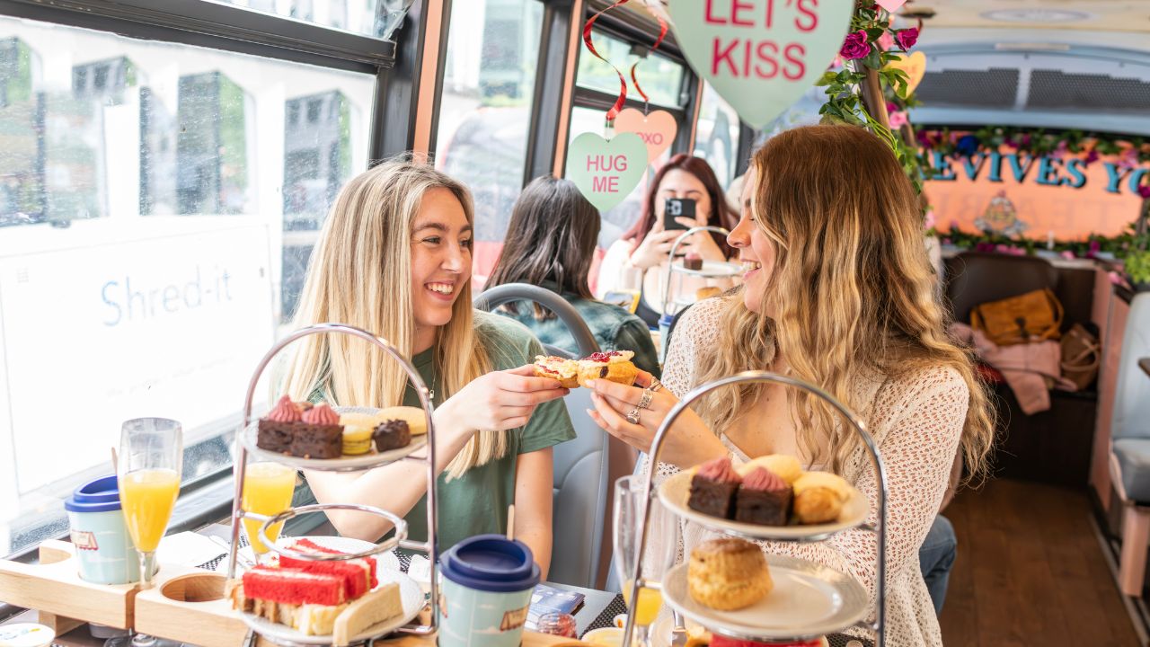 Bring your loved ones to a panoramic tour of London for a unique experience aboard the Afternoon Tea Bus Tour. © Visit London/Michael Barrow Two people cheers drinks aboard a valentines themed afternoon tea bus tour