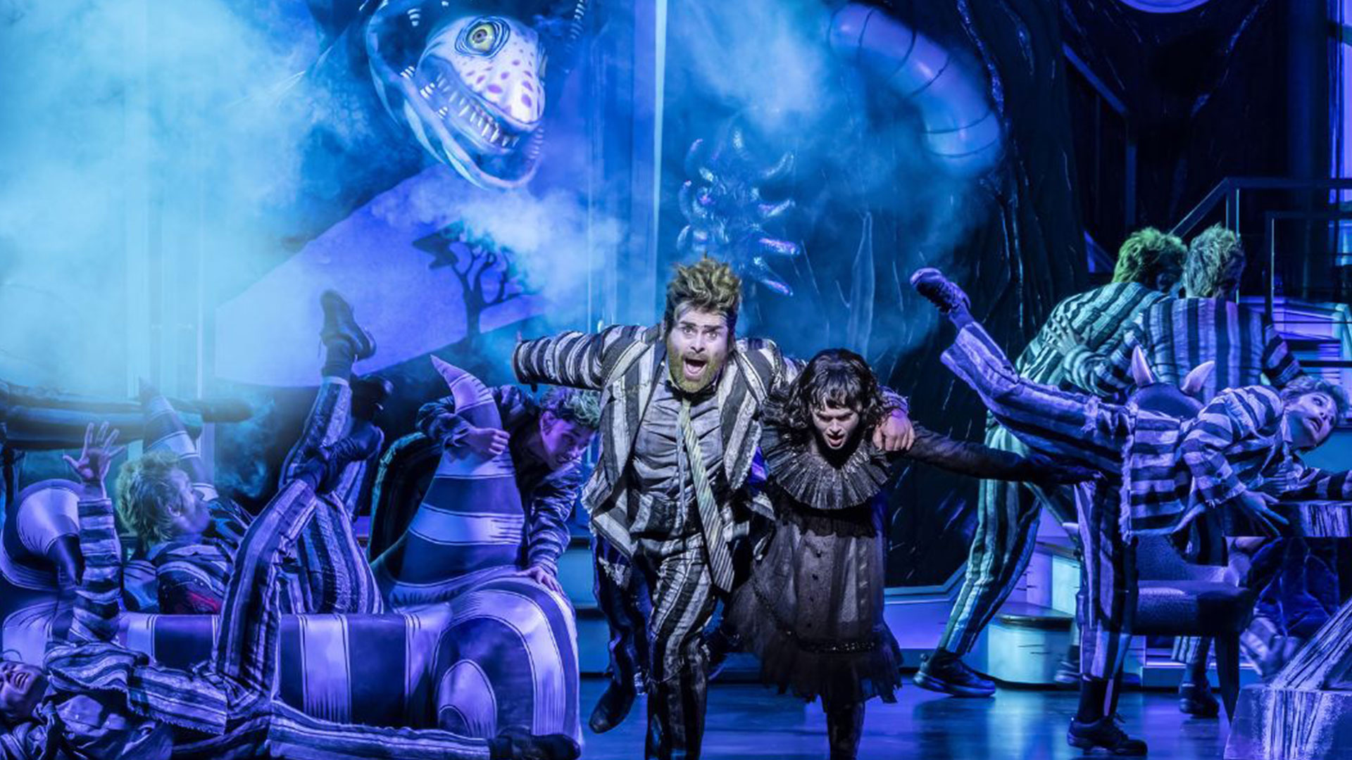 See Beetlejuice the Musical, a new stage adaptation of the classic Tim Burton film, in which Lydia Deetz finds herself drawn into the underworld. Image courtesy of London Theatre Direct. The two actors playing in Beetlejuice — one wearing the iconic stripy suit, the other a black lace dress — run onto the stage, fleeing from a giant snake.
