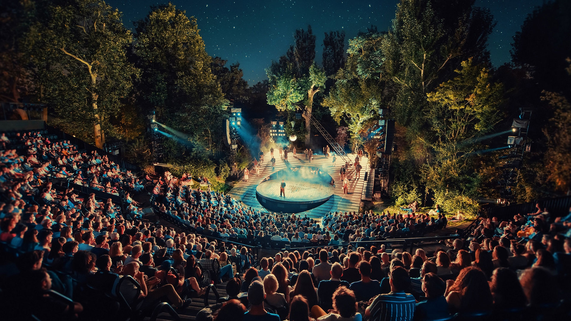Choose from a selection of plays to watch under the stars at the Regent's Park Open Air Theatre. Image courtesy of David Jensen/ Feast Creative Web. The Open Air Theatre in Regent's Park is filled with spectators at night watching one of the performances programmed.