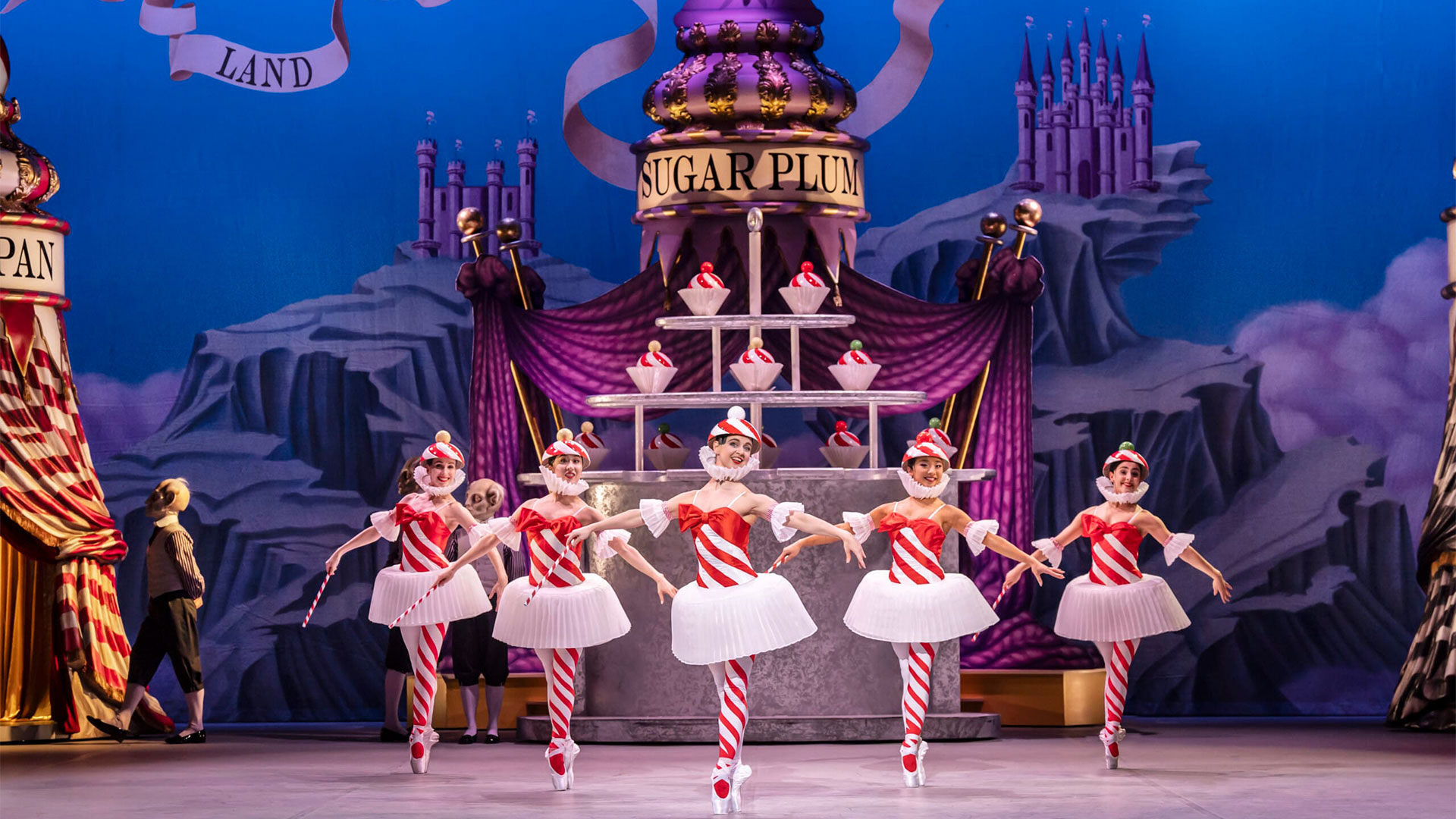 Watch the English National Ballet's magical production of The Nutcracker at London Coliseum. Image courtesy of London Theatre Direct. During the production of The Nutcracker Ballet at the London Coliseum, five ballet dancers wearing red and white striped tights and bodices are dancing on stage.