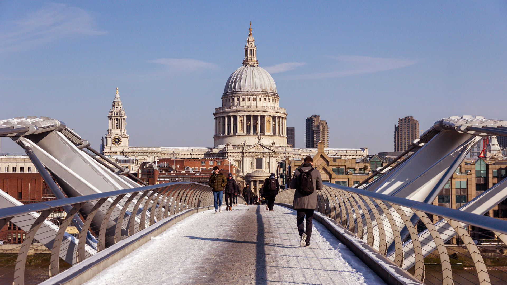 Millennium Bridge and St Paul's Cathedral on a winter's day. Image courtesy of Shutterstock. People walking across the London Millennium Bridge in the snow against the backdrop of St Paul's Cathedral.